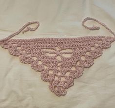 a pink crocheted triangle on a white sheet