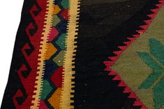 a close up of a multi colored rug with leaves on it's side and an arrow in the middle