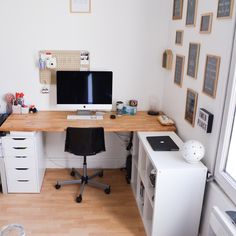 a desk with a computer on top of it in front of a window and other office supplies