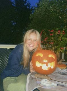 a woman sitting on a bench holding a carved pumpkin