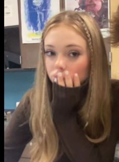 a woman with long blonde hair sitting in front of a computer desk and looking at the camera