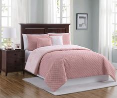 a bed with pink comforter and pillows in a room