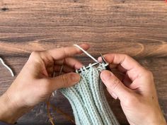 someone is knitting something on a wooden surface