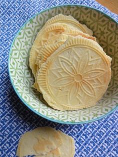 some kind of food in a bowl on a blue and white table cloth next to it