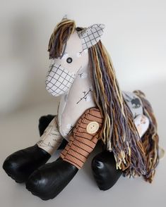 a stuffed toy horse sitting on top of a white table next to a black boot