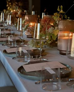 a long table is set with candles and place settings for dinner guests to sit at