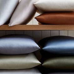 four pillows stacked on top of each other in front of a shelf with several different colors