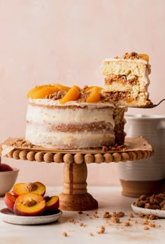 a cake with peaches and crumbs is on a wooden stand next to other desserts