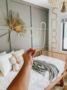 a person holding up a metal object in front of a baby's crib