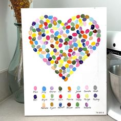 a white card with a heart made out of colorful confetti dots on it