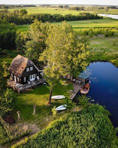 an aerial view of a house with boats in the water and trees around it, surrounded by lush green grass