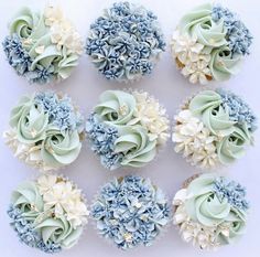 cupcakes decorated with blue and white flowers on a table in front of a white background