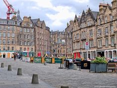 an old town square with people sitting at tables in the middle and buildings on both sides