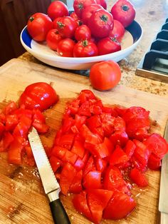 chopped up tomatoes on a cutting board next to a knife and bowl of fresh cut tomatoes