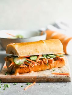 a sandwich with meat and vegetables on a cutting board