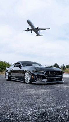 a large jetliner flying over a black sports car