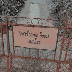 a welcome home sign is posted on an iron gate in front of some bushes and trees