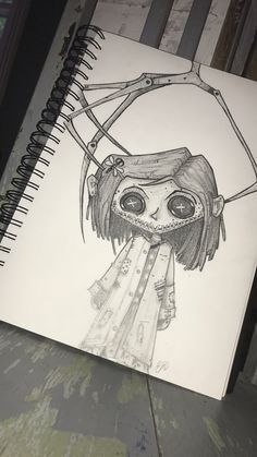 a drawing of a girl with scissors on her head and eyes drawn in pencil next to a spiral notebook