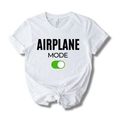 Take your style to new heights with our 'Airplane Mode' White Edition Shirt. Crafted for the modern traveler, this sleek, jet-black tee embodies the essence of uninterrupted journeys. Made with soft, breathable fabric, it ensures comfort whether you're crossing time zones or just relaxing. Disconnect, unwind, and let the world know you're on airplane mode. Features: Short Sleeve Crew Neckline Relaxed Fit Lightweight Feel 100% Cotton Care and Maintenance: Please hand wash and drip dry Shipping No Casual Black Top For Travel, On Airplane, Airplane Mode, Time Zones, Drip Dry, Jet Black, Casual Wardrobe, Shirt White, Unisex Shirt