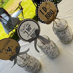 three mason jars filled with dirt sitting on top of a white tablecloth covered field