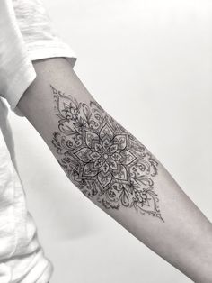 a woman's arm with a tattoo on it that has an intricate flower design