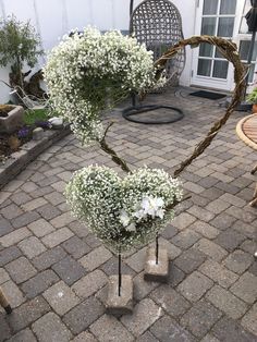 two heart shaped vases with baby's breath flowers in them on a brick patio