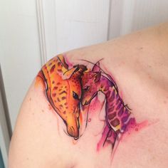 two giraffe tattoos on the back of a woman's shoulder