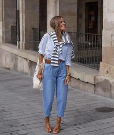 Embrace a European aesthetic with this stylish fall outfit. The combination of a striped sweater draped over a light blue button-up shirt and high-waisted jeans creates a look that is both casual and polished. The addition of brown leather sandals and accessories enhances the overall chic vibe. Perfect for a day of exploring the city or a casual lunch with friends, this outfit is versatile and fashionable.  Photo credit by: @woman_citystyles Striped Button Up Shirt Outfit, Blue Stripes Outfit, Light Blue Shirt Outfit, Blue Denim Jeans Outfit, Blue Striped Shirt Outfit, Fall Outfits Cute, Outfits With Striped Shirts, Business Looks, Blue And White Striped Shirt