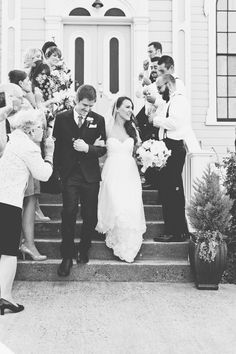 a bride and groom walking down the steps with their guests in front of a church