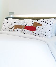 a bed with white sheets and a brown dog pillow on it's headboard