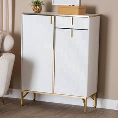 a white cabinet sitting next to a chair in a living room with a plant on top of it