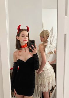 a woman taking a selfie in front of a mirror with devil horns on her head