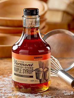 a bottle of maple syrup next to a whisk