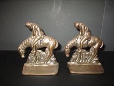 two bronze figurines of horses on a black table