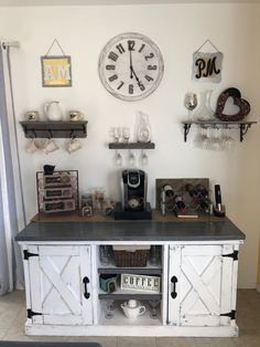 a kitchen with a large clock on the wall next to shelves and coffee maker in front of it