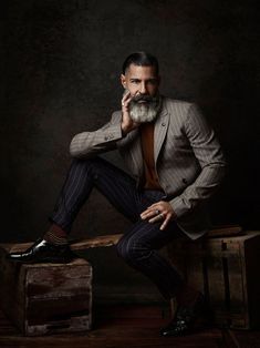 a man with a beard sitting on top of a wooden bench wearing a suit and tie