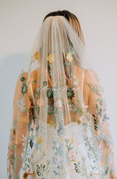 the back of a bride's veil with flowers and leaves all over her dress