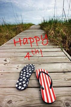 two flip flops sitting on top of a wooden dock with the words happy 4th written in red, white and blue