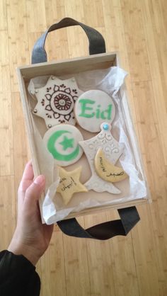 someone holding up a box with decorated cookies in it