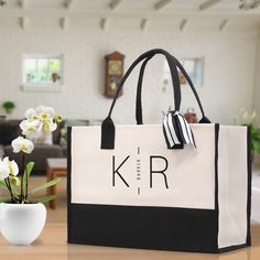 a white and black bag sitting on top of a table next to a vase with flowers