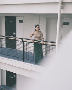 a man standing on top of a balcony next to a black door and wearing headphones