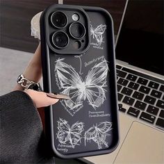 a woman holding up a phone case with butterflies on it and the back cover is black