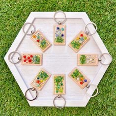 a white tray topped with lots of different types of keychains on top of green grass