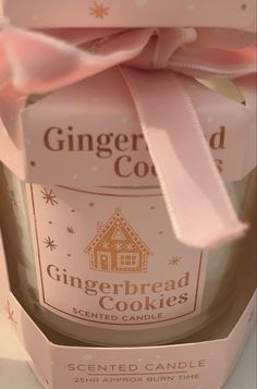 a gingerbread cookie in a glass jar with a pink ribbon around the top and inside