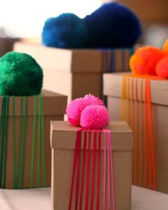 three boxes with different colored pom poms on them