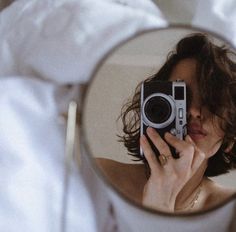 a woman taking a selfie in the mirror while she is holding her camera up to her face