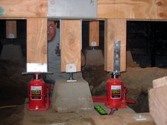 a man is working on two red jacks in a room with wooden walls and beams