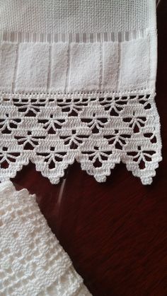 two pieces of white crocheted cloth on a wooden table