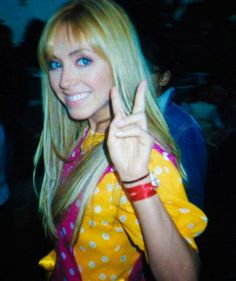 a woman with long blonde hair giving the peace sign