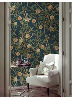 a white chair sitting in front of a green wallpapered with birds and flowers